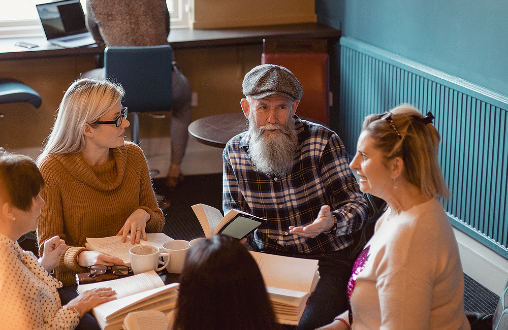 Een oudere man in overleg met zijn jongere collega's 