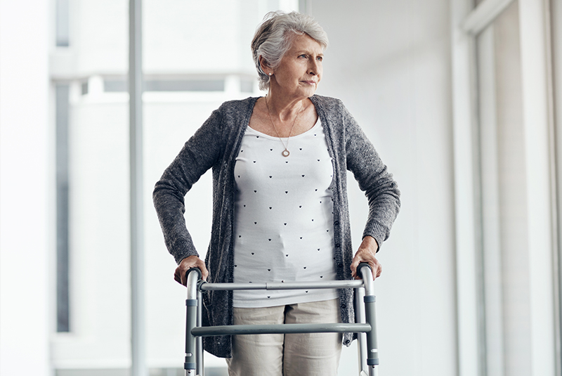 Een vrouw in het woonzorgcentrum wandelt met haar rollator