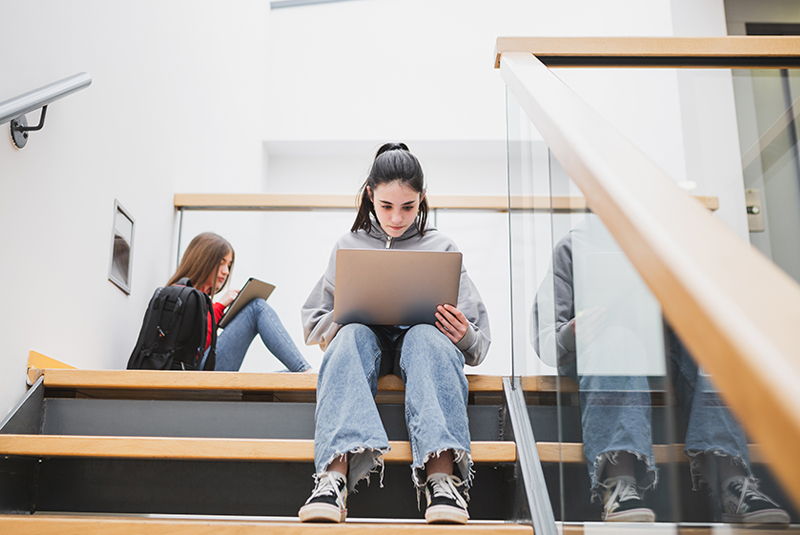 Een jonge studente zit op de trap in haar school