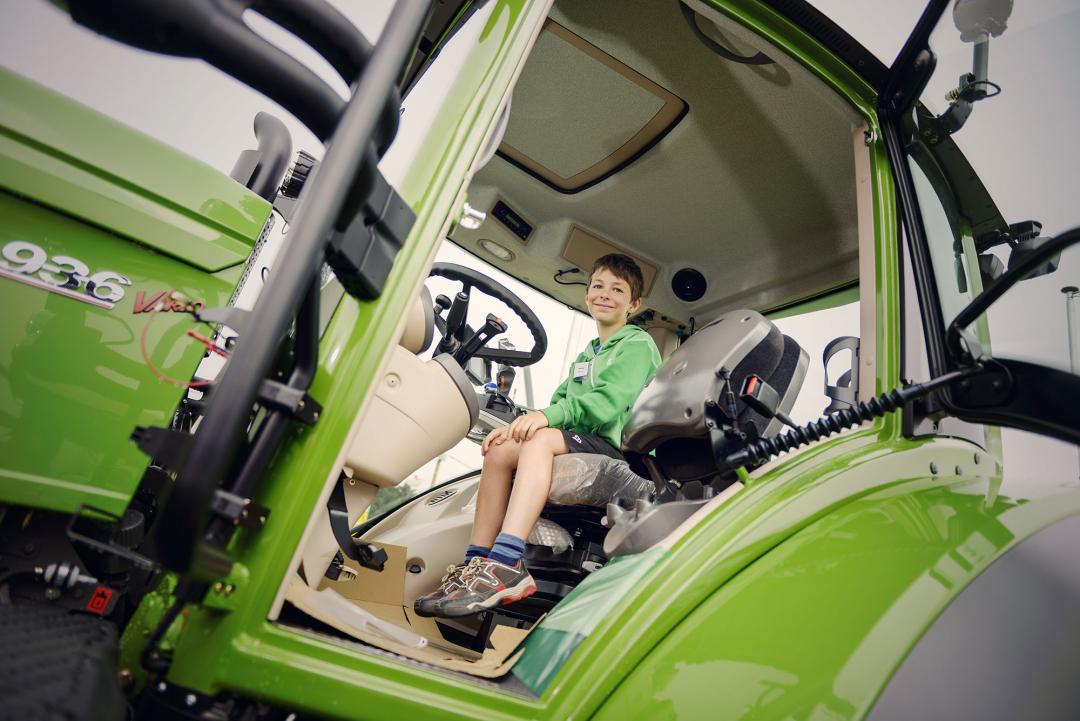 Jongen in een grote tractor op de landbouwbeurs
