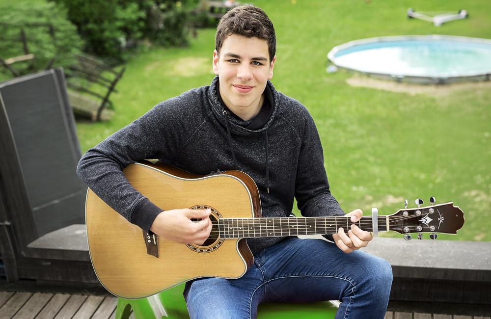 Een jonge kerel speelt op zijn gitaar