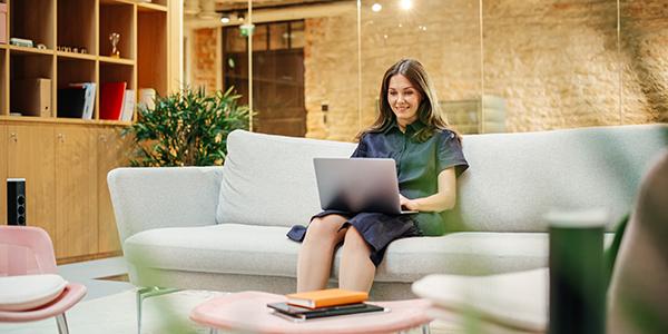 Jonge vrouw kijkt ontspannen op haar laptop in de zetel