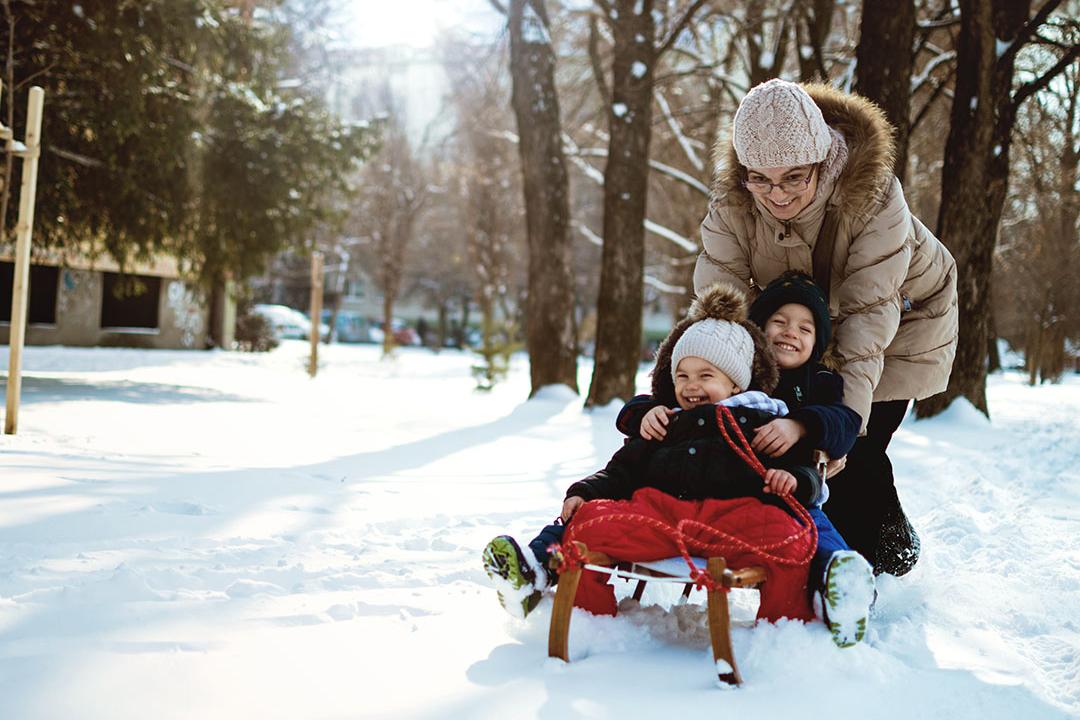 Vrouw speelt met haar 2 kindjes in de sneeuw