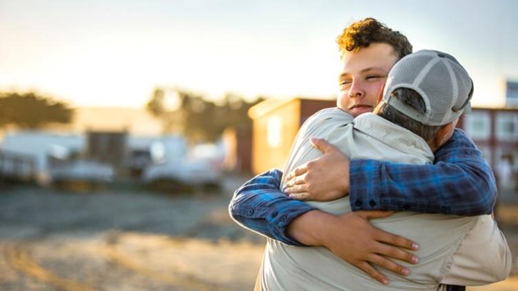 Vader knuffelt zijn tienerzoon