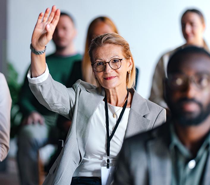Vrouw in de zaal steekt hand omhoog om een vraag te stellen