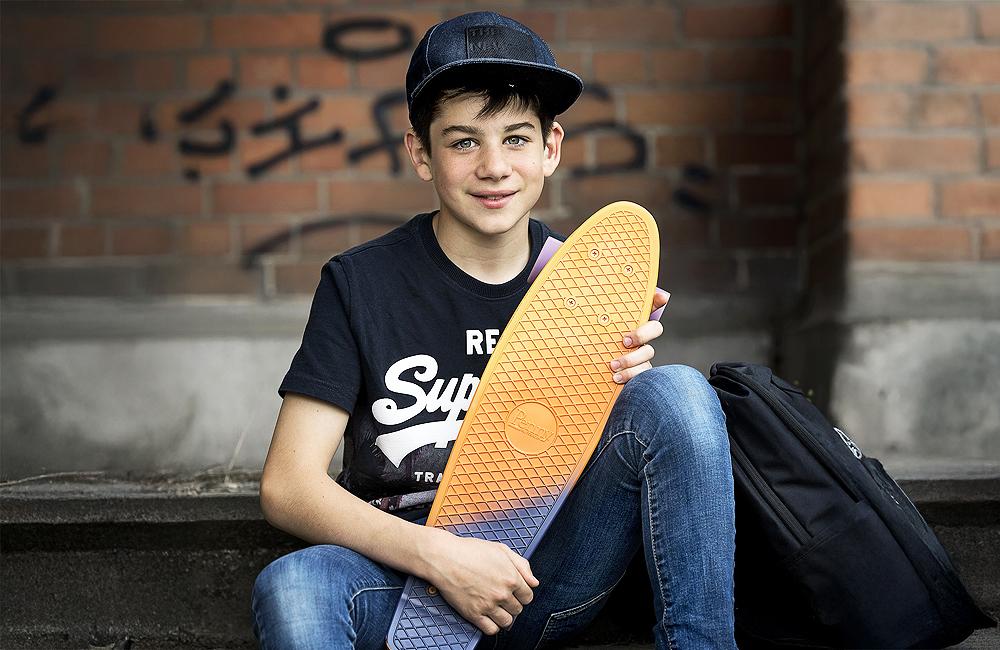 Een lachende jongen met pet en skateboard