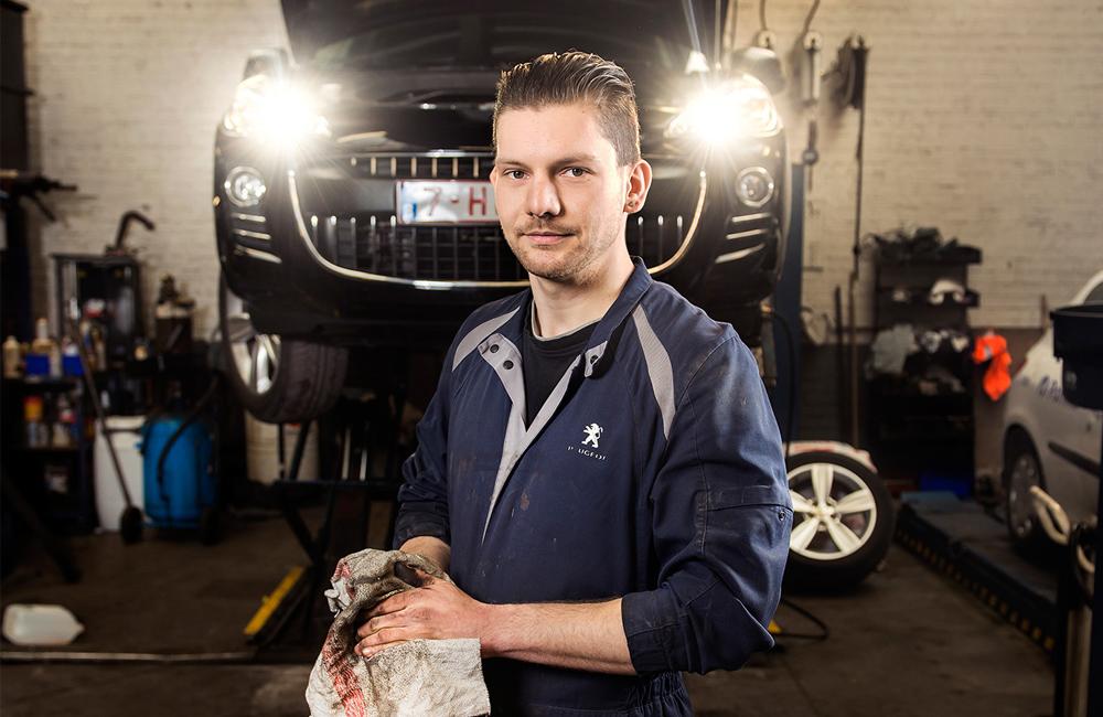 Een jonge garagist werkt aan het onderhoud van een wagen