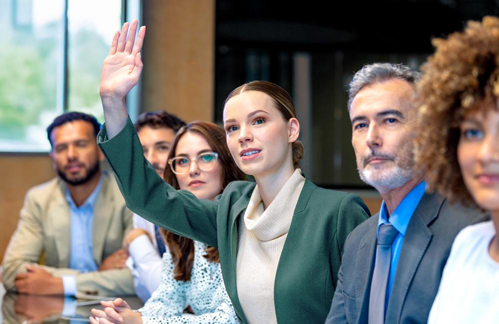 Een jonge vrouw vraagt het woord tijdens een vergadering