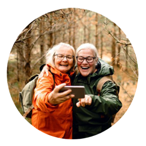 2 oudere dames nemen lachend een selfie in het bos