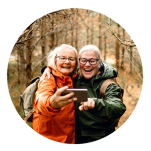 2 oudere dames nemen lachend een selfie in het bos