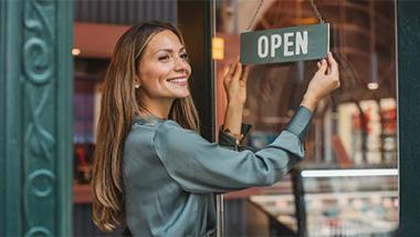 La vendeuse retourne le panneau « ouvert » sur la porte du magasin avec un sourire