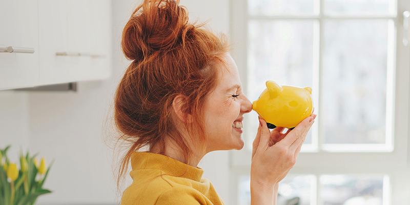 Jonge vrouw is gelukkig met haar geel spaarvarkentje