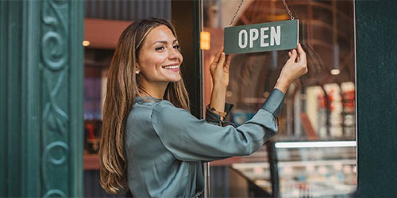 La vendeuse retourne le panneau « ouvert » sur la porte du magasin avec un sourire