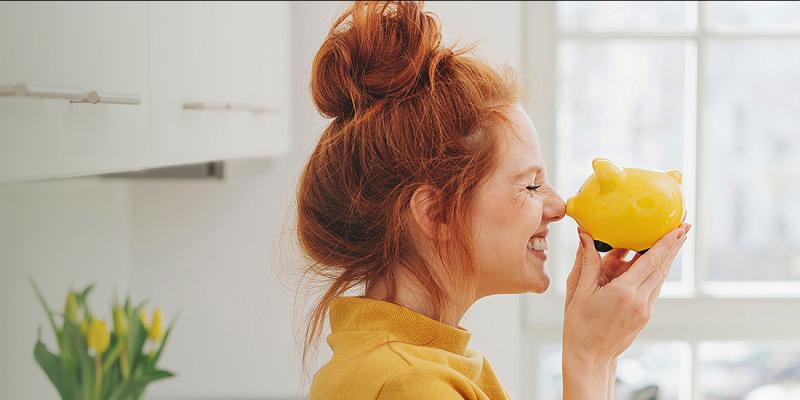 Jonge vrouw is gelukkig met haar geel spaarvarkentje