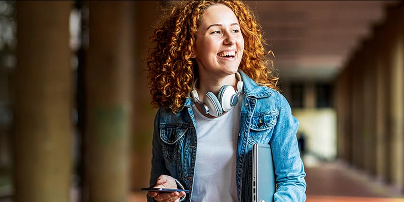 Lachende jongedame met hoofdtelefoon en smartphone in de hand