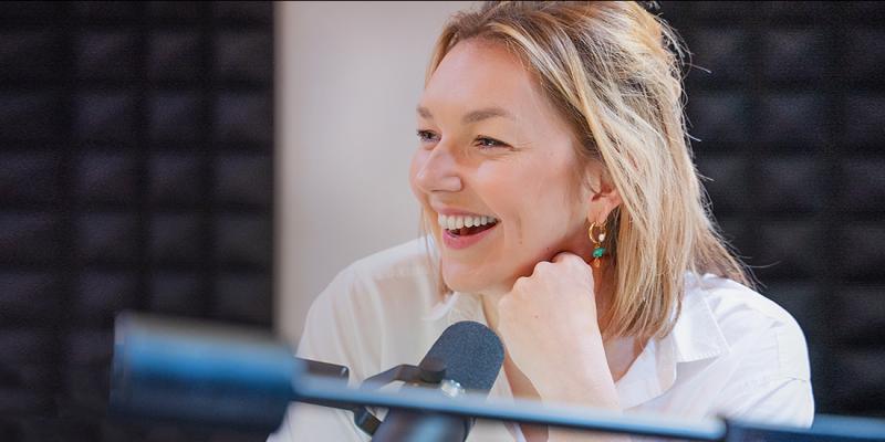Jonge vrouw met microfoon lachend in de opnamestudio