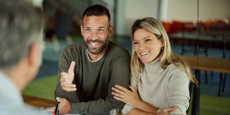 Un jeune couple écoute avec fascination leur agent bancaire de Crelan
