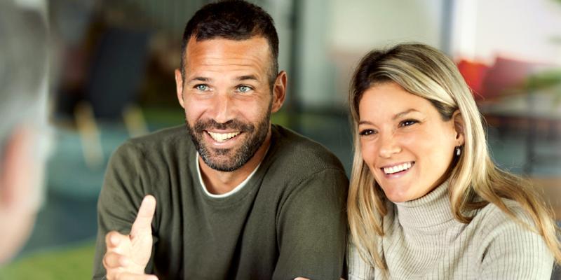 Un jeune couple écoute avec fascination leur agent bancaire de Crelan
