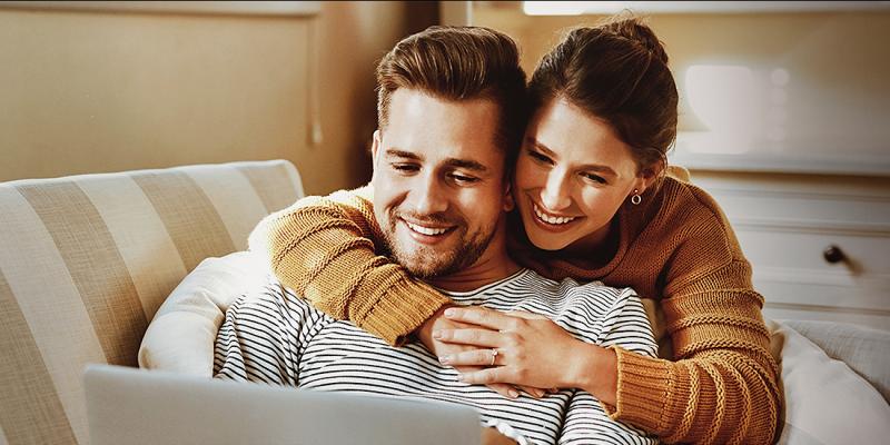 Een jong koppel in de zetel zoekt informatie op de laptop