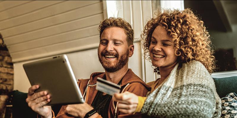 Een jong koppel met Crelan-bankkaart en laptop in de zetel