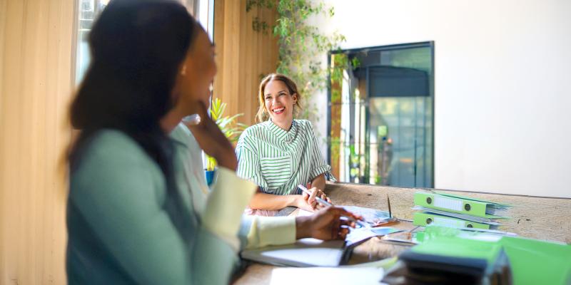 2 vrouwen lachend in gesprek op kantoor