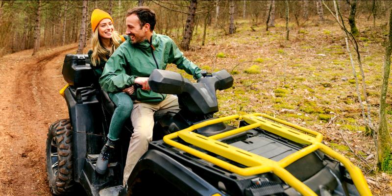 Un couple heureux fait du quad à travers la forêt