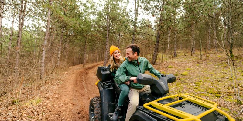 Vrolijk koppel rijdt op een quad door het bos