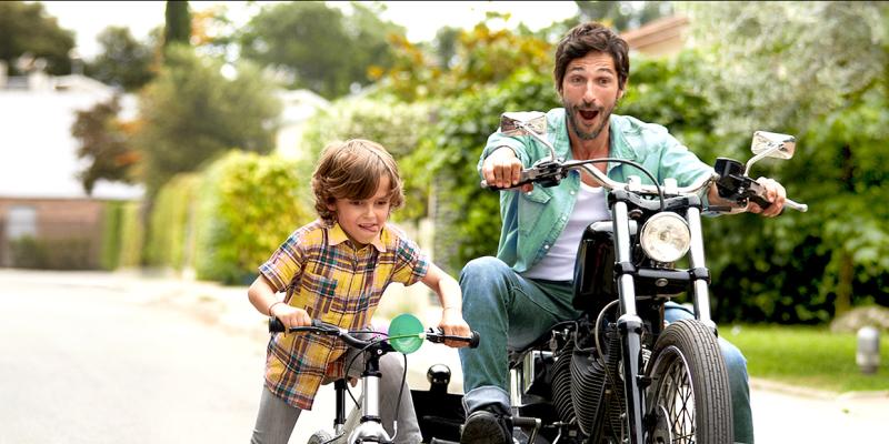 Un père sur une moto et son fils sur un vélo roulent côte à côte