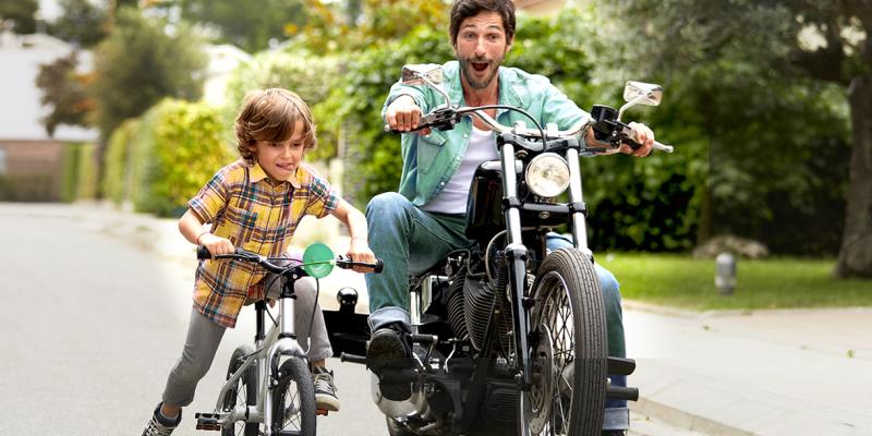 Vader op zijn motor en zoontje op zijn fiets naast elkaar