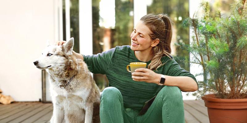 Vrouw streelt haar hond op haar tuinterras