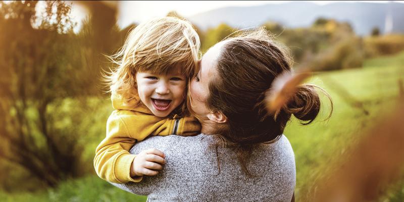 Une jeune mère serre sa petite fille dans ses bras à l'extérieur