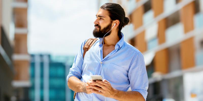 Man met baard luistert met oortjes in naar podcast