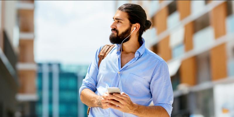 Un homme barbu écoute un podcast avec des écouteurs