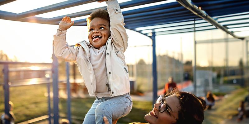 Un enfant joue avec sa maman sur une plaine de jeux 