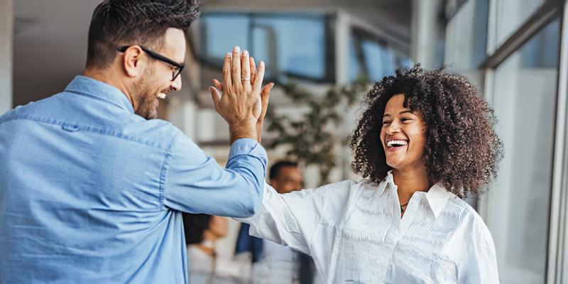 Een gelukkige vrouw geeft een high-five aan een collega