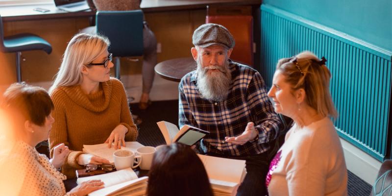 Een oudere man in overleg met zijn jongere collega's
