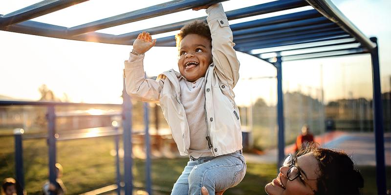 Un petit garçon joue joyeusement sur un portique d'escalade avec sa mère