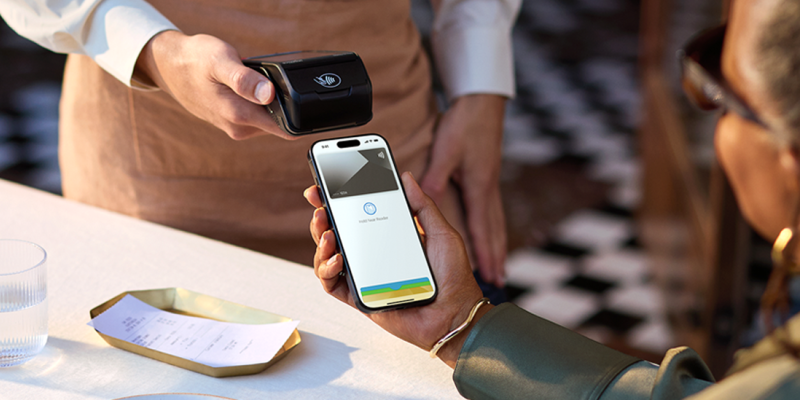 Een vrouw op terras betaalt haar rekening contactloos met Apple Pay