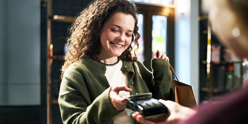 Een jonge vrouw in een boekenwinkel betaalt contactloos met Google Pay