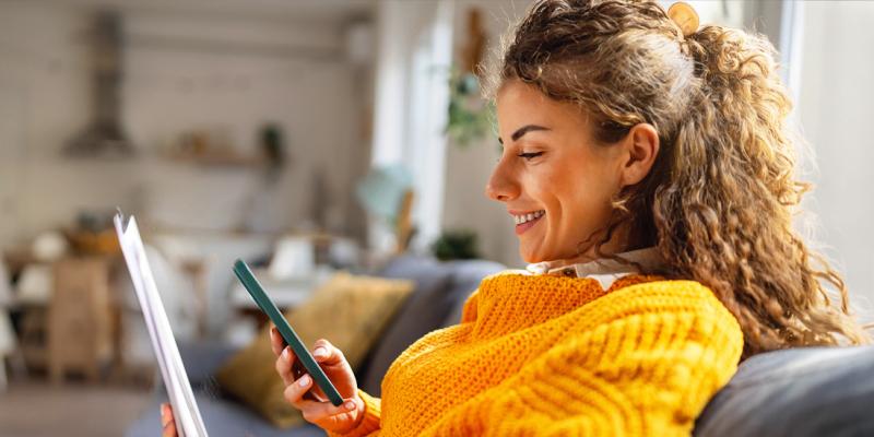 Une jeune femme portant le maillot jaune regarde son smartphone en souriant sur son siège