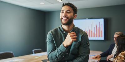 Een jongeman met baard geeft een presentatie aan zijn collega's