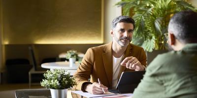 Een man met baard bespreekt de productscores van Crelan met zijn klant