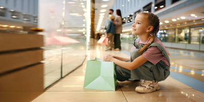 Une petite fille regarde avec émerveillement la vitrine d'un magasin dans un centre commercial