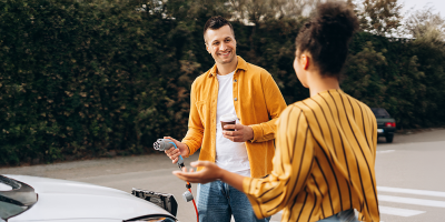 Un couple se tient près de sa voiture électrique pendant qu’il la recharge