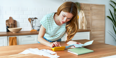 Une femme calcule ses dépenses à la table de la cuisine