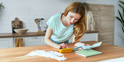 Een vrouw berekent haar uitgaven aan de keukentafel