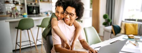 Zoontje knuffelt zijn papa aan de laptop