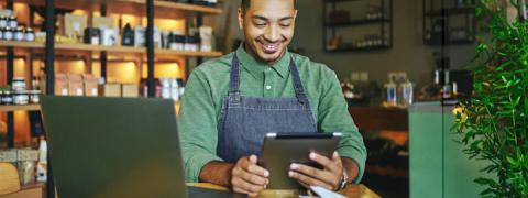 Lachende man bekijkt zijn bankzaken op een tablet