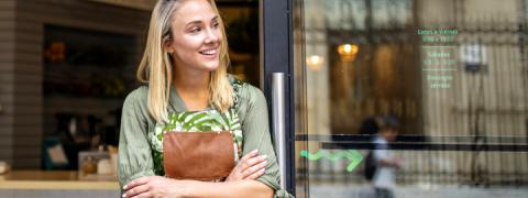 Jonge, blonde vrouw lachend voor haar vitrine