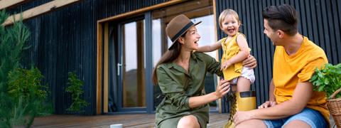 un couple avec un enfant devant leur nouvelle maison